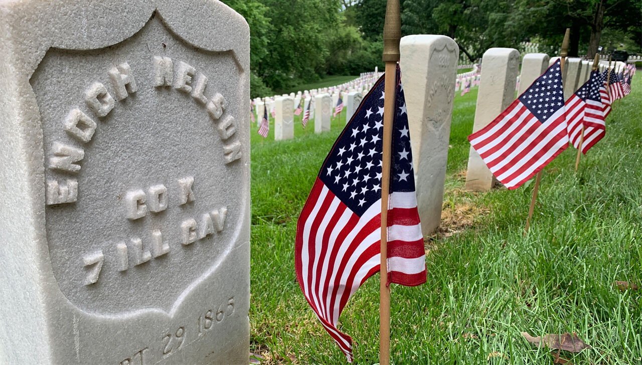 Volunteers place American flags on the graves of more than 6,000 soldiers at Cave Hill Cemetery